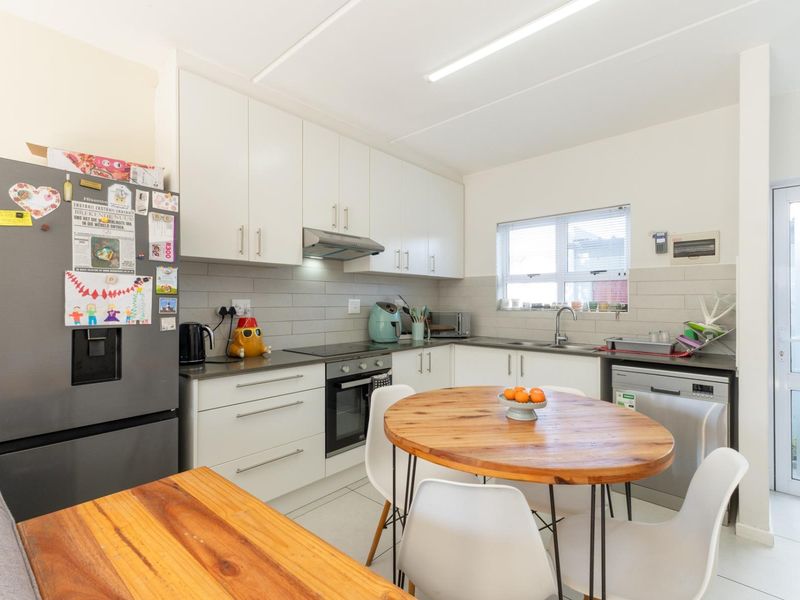 A functional kitchen featuring white cabinetry, a tiled backsplash, built-in oven and hob, and direct access to an exterior door.