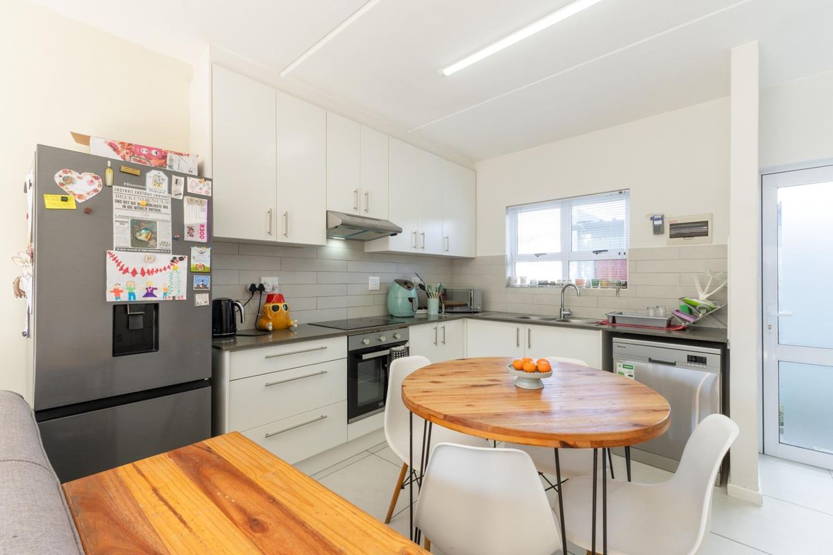 A functional kitchen featuring white cabinetry, a tiled backsplash, built-in oven and hob, and direct access to an exterior door.