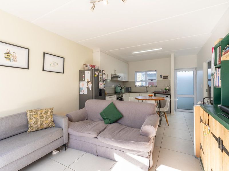 Open-plan living and kitchen area featuring tiled flooring, built-in cabinetry, and direct access to an exterior door.
