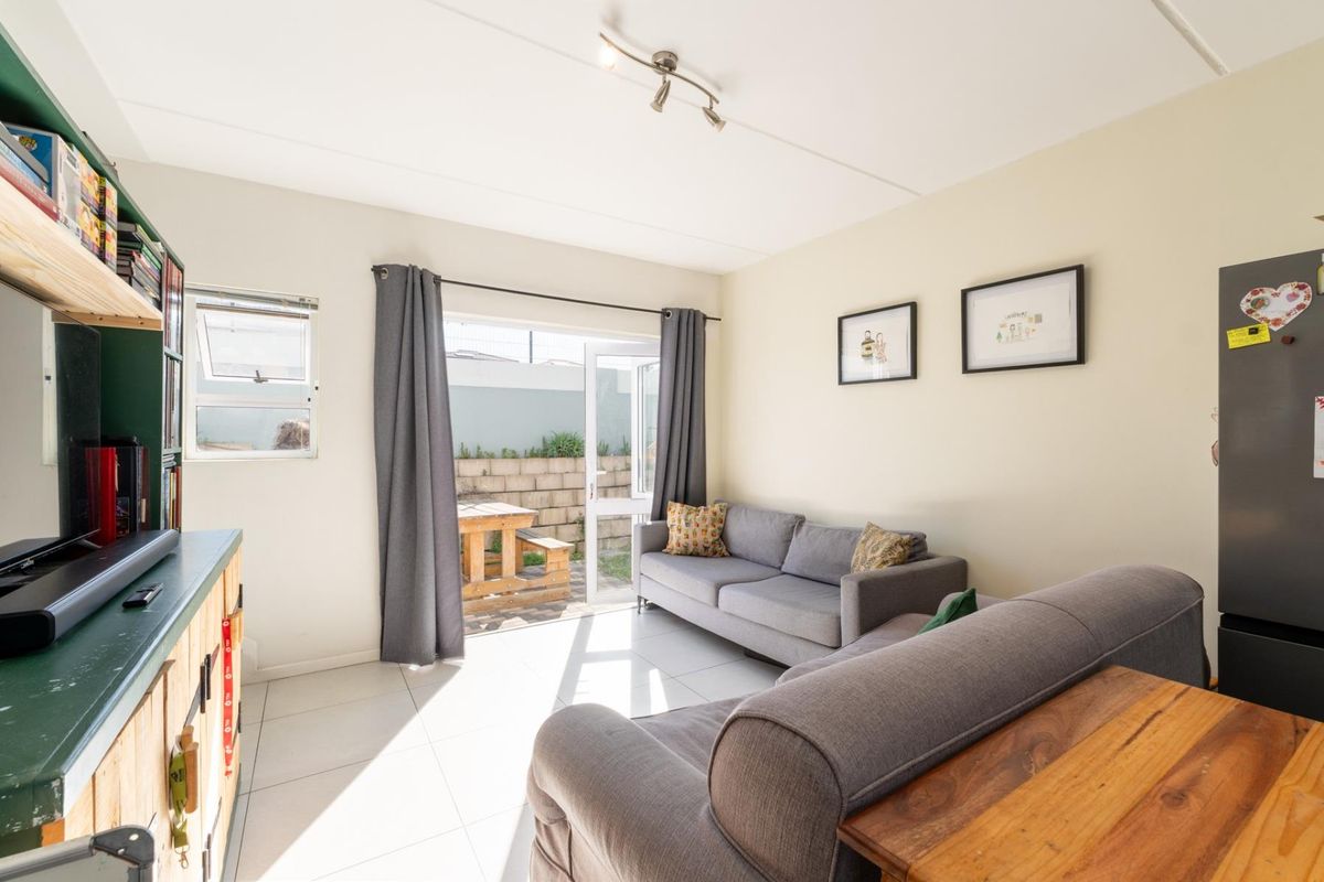 A bright living room featuring tiled flooring and a sliding glass door providing direct access to the rear patio area.