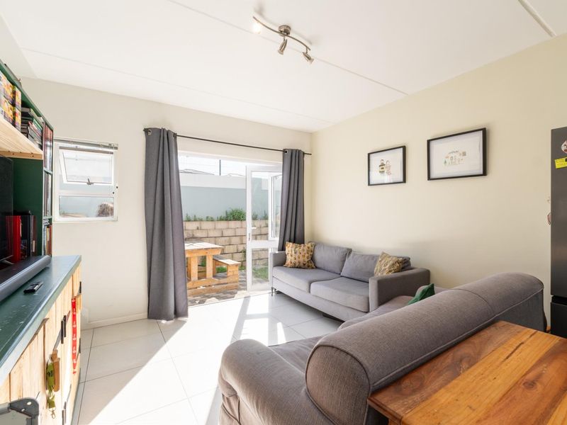 A bright living room featuring tiled flooring and a sliding glass door providing direct access to the rear patio area.