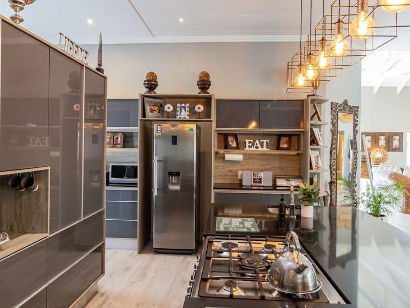 Modern open-plan kitchen featuring sleek cabinetry, a central island with a gas cooktop, and high-quality finishes, seamlessly flowing into the adjacent living area.