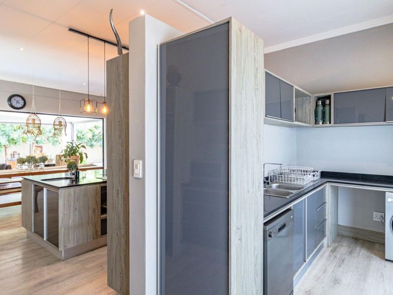 Modern open-plan kitchen and living area featuring contemporary cabinetry, a central island, and integrated appliances with a seamless flow to the outdoor space.