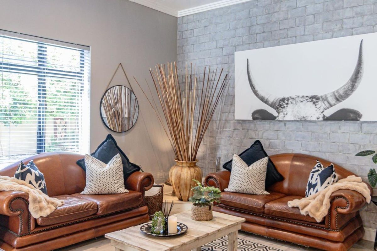 A well-maintained living room featuring a textured grey exposed brick feature wall and large window with venetian blinds.