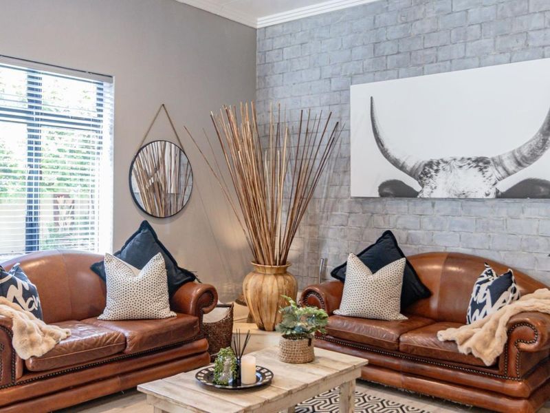 A well-maintained living room featuring a textured grey exposed brick feature wall and large window with venetian blinds.