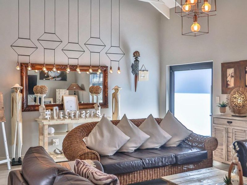 A bright living room featuring a high vaulted ceiling with exposed rafters, modern pendant lighting, and a large sliding glass door providing natural light.