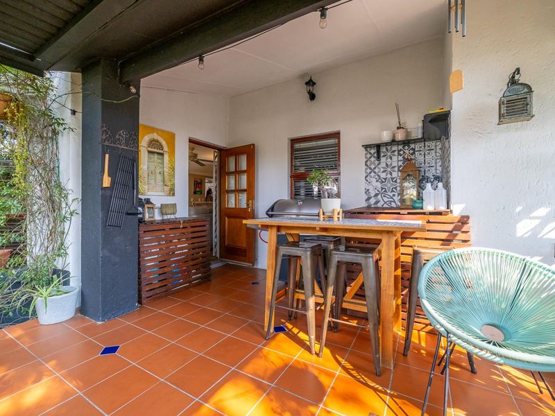 A covered outdoor patio area featuring terracotta-style tiled flooring and decorative wall accents, providing a functional space for outdoor dining and relaxation.