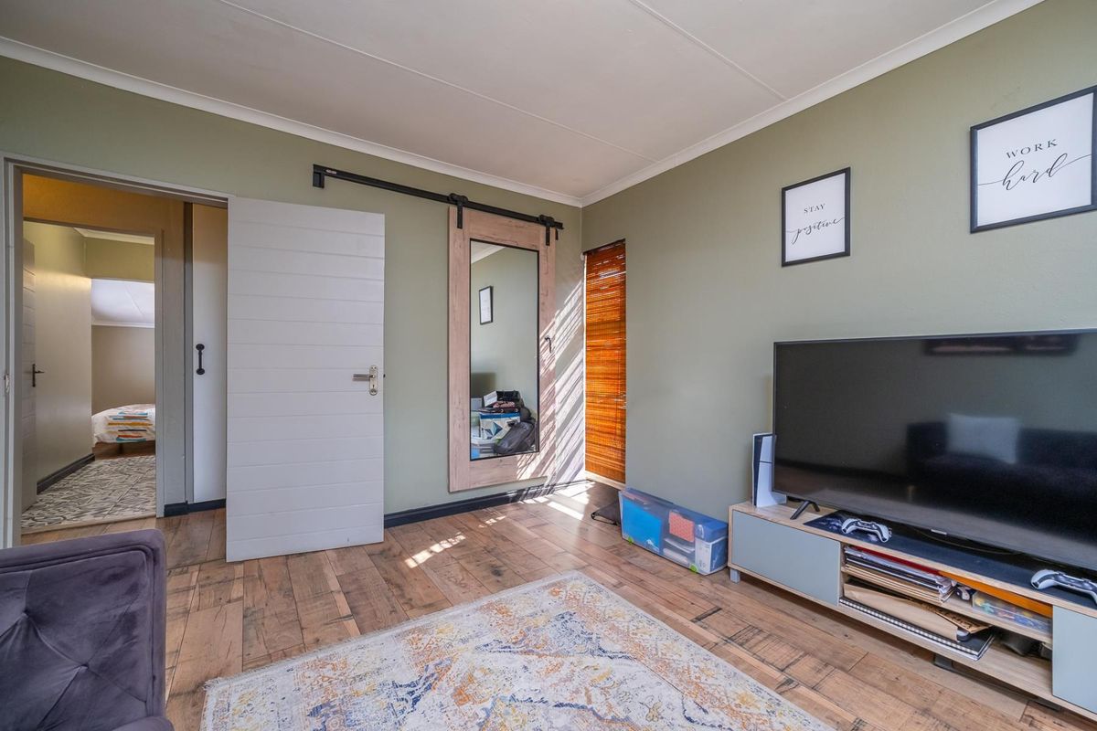 A well-maintained bedroom featuring timber flooring, a sliding barn door, and neutral wall tones, offering a comfortable and functional living space.