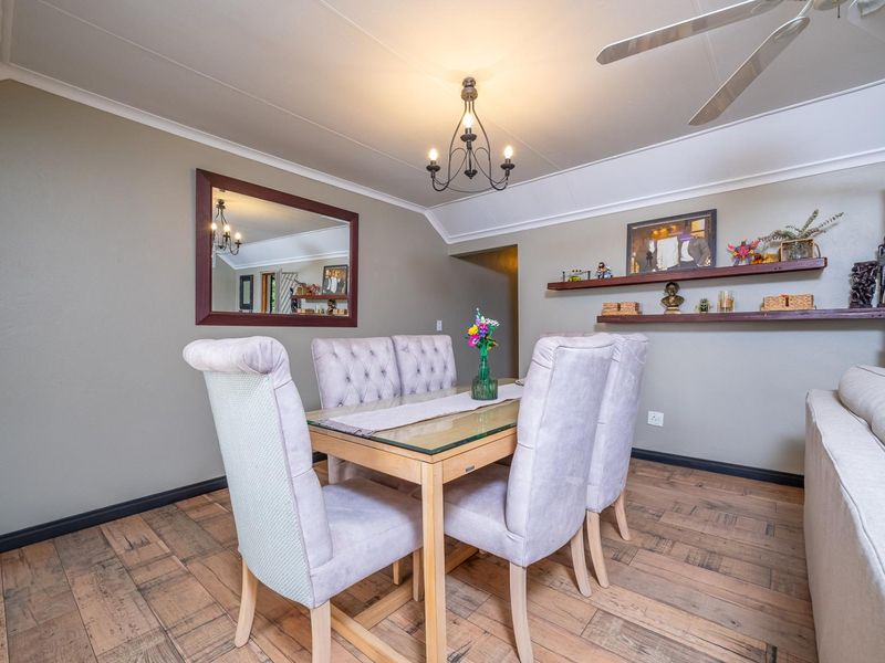 A well-maintained dining area featuring wood-look flooring, a central chandelier, and a ceiling fan, creating a comfortable and functional space for meals.