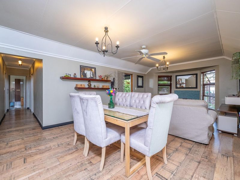 Spacious open-plan living and dining area featuring tiled flooring, a ceiling fan, and a tiled fireplace surround, creating a comfortable and functional living space.