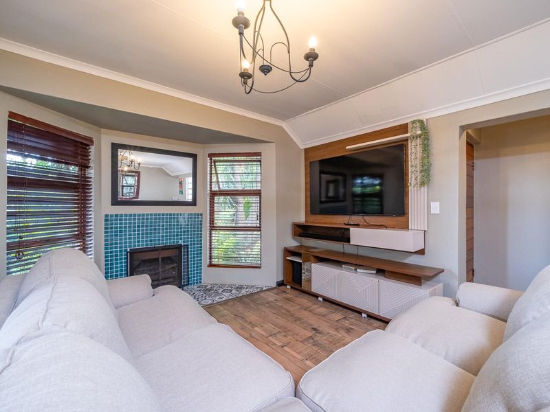 Cozy living room featuring a tiled fireplace, built-in media cabinetry, timber flooring, and a decorative chandelier.