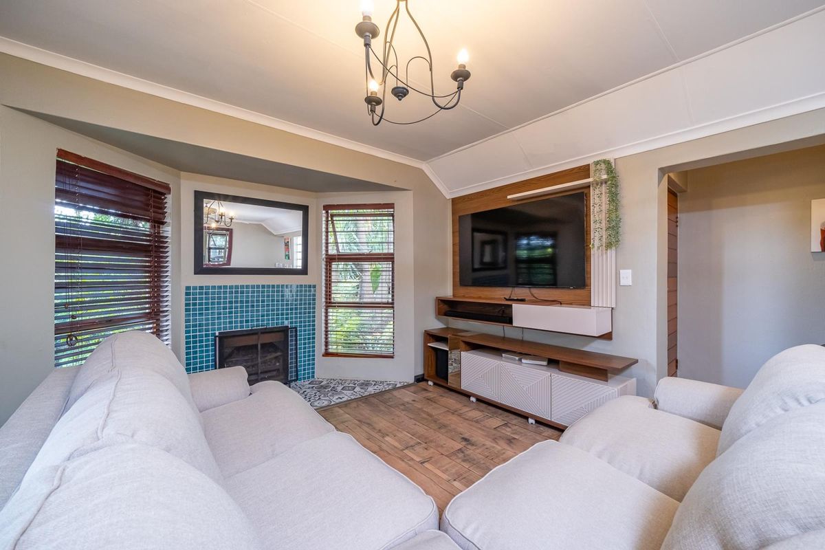 Cozy living room featuring a tiled fireplace, built-in media cabinetry, timber flooring, and a decorative chandelier.