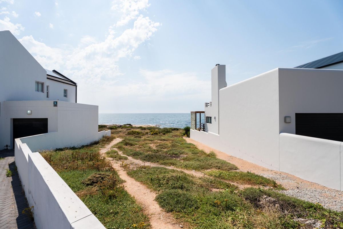 A scenic view of the ocean framed by modern residential architecture, showcasing the coastal landscape and direct sea access.