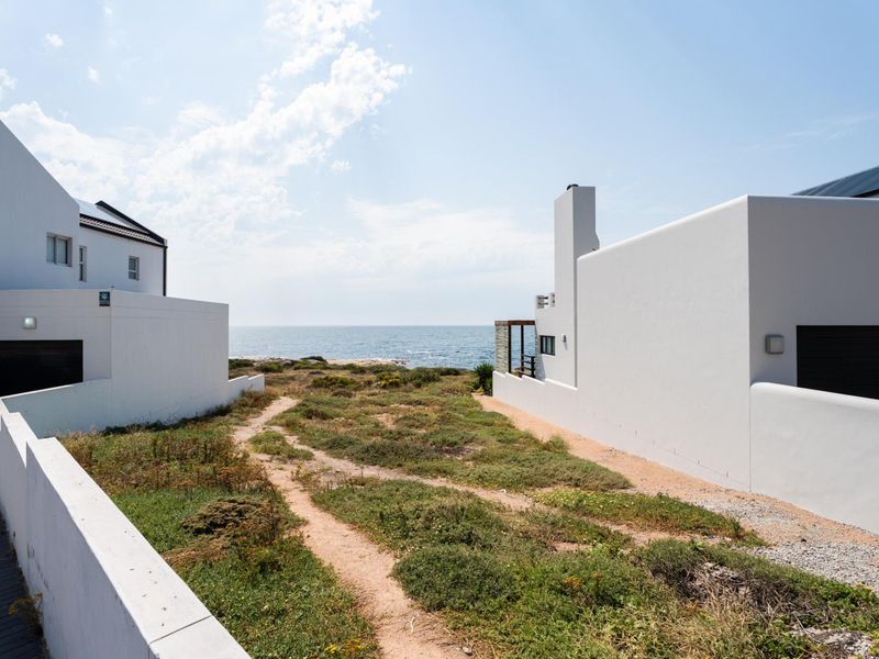 A scenic view of the ocean framed by modern residential architecture, showcasing the coastal landscape and direct sea access.