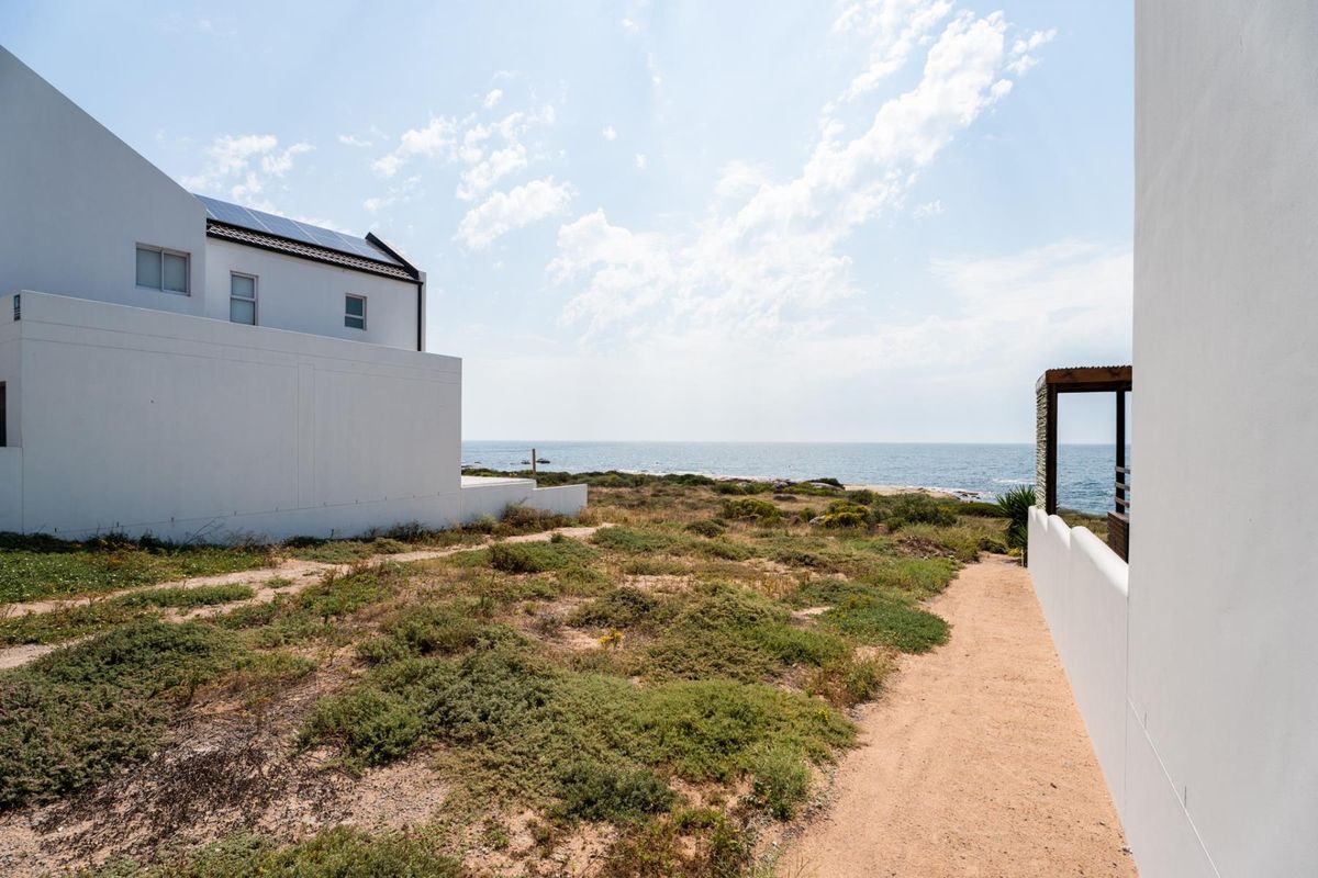 A scenic view of the coastline from the property, featuring a well-maintained exterior path and proximity to the ocean.