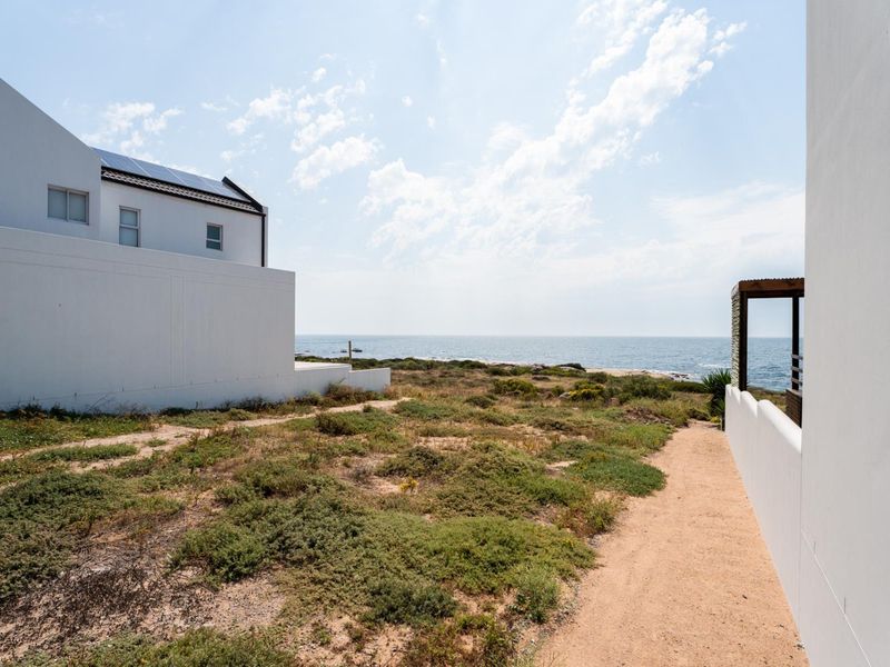 A scenic view of the coastline from the property, featuring a well-maintained exterior path and proximity to the ocean.