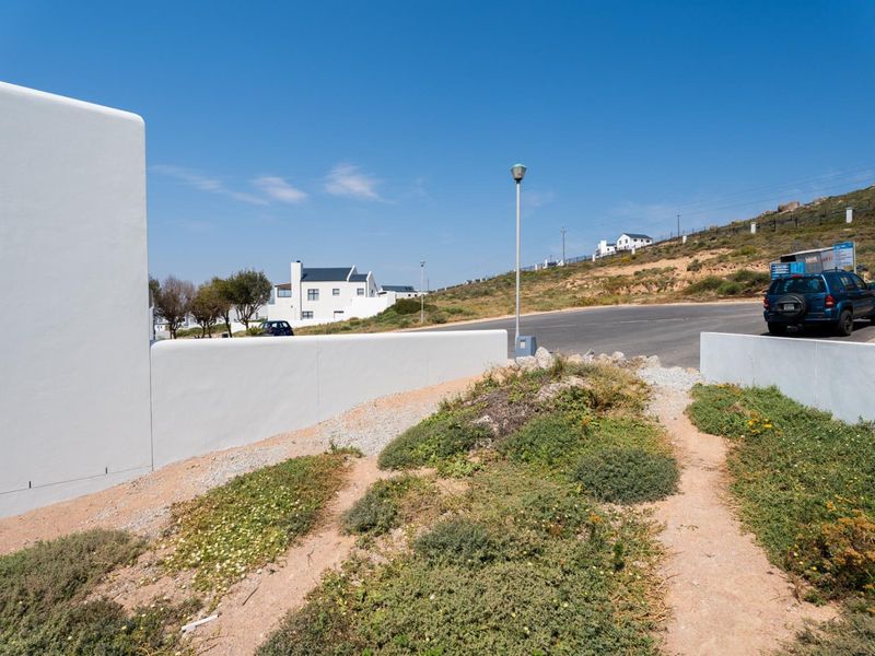 View of the property frontage showing a clean boundary wall, access path, and established street infrastructure in a residential estate setting.