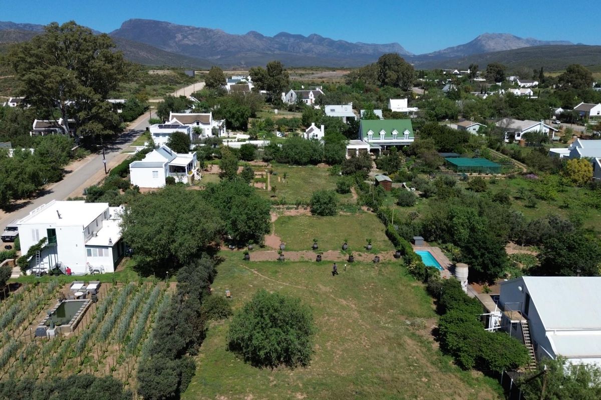 Aerial view of a residential property featuring a large garden, swimming pool, and surrounding neighbourhood landscape with mountain views.