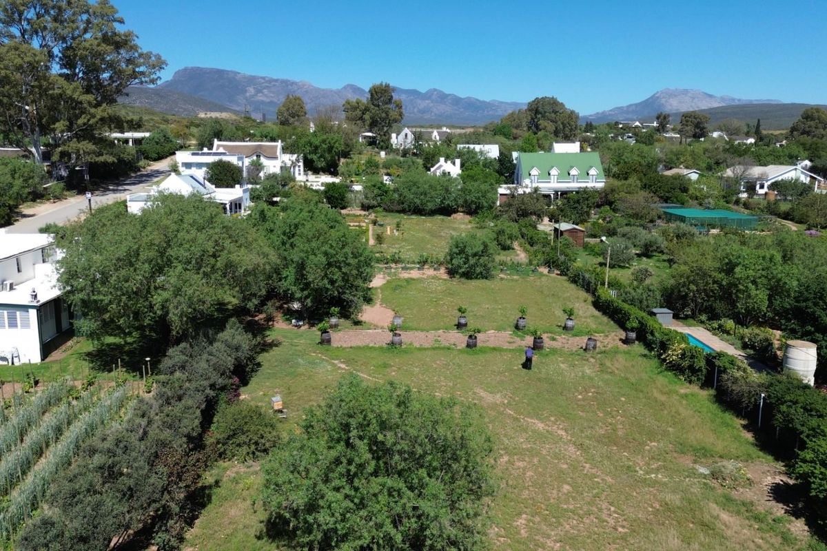 An aerial view of a spacious residential plot featuring established trees, garden landscaping, and mountain views in a quiet neighborhood setting.