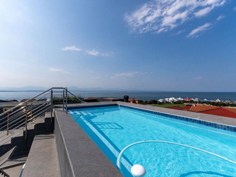 A rooftop swimming pool featuring modern stainless steel railings and panoramic ocean views, providing a high-end outdoor leisure space.