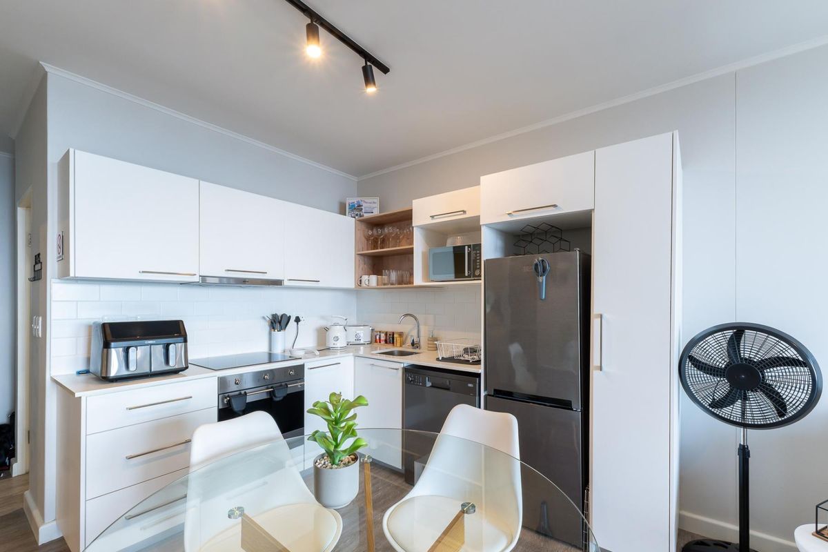 Modern kitchen featuring white cabinetry, subway tile backsplash, integrated appliances, and efficient track lighting in a clean, functional layout.