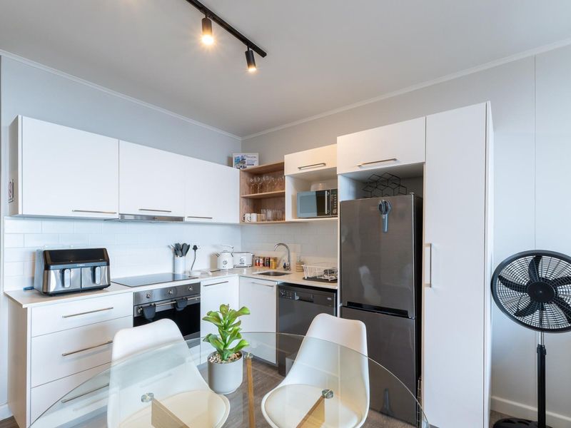 Modern kitchen featuring white cabinetry, subway tile backsplash, integrated appliances, and efficient track lighting in a clean, functional layout.