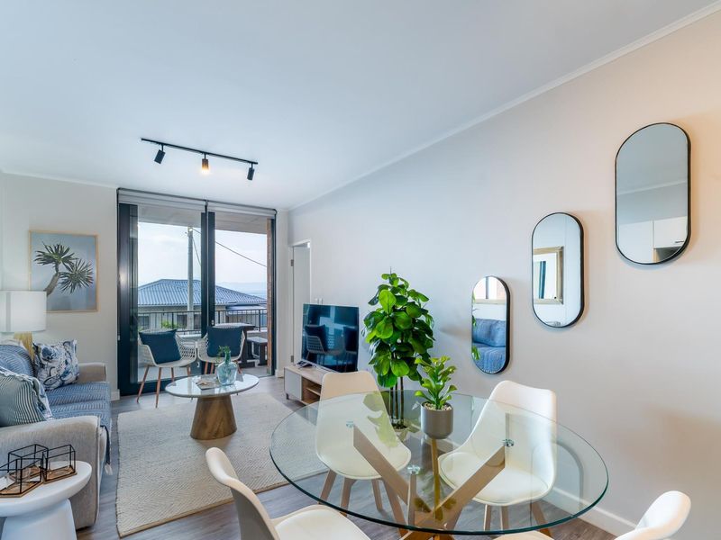 Modern open-plan living and dining area featuring track lighting, laminate flooring, and a large sliding glass door leading to an outdoor balcony.