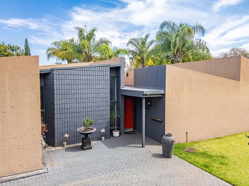 Front exterior view of the property featuring a paved driveway, covered entrance, and a modern architectural design with contrasting wall finishes.