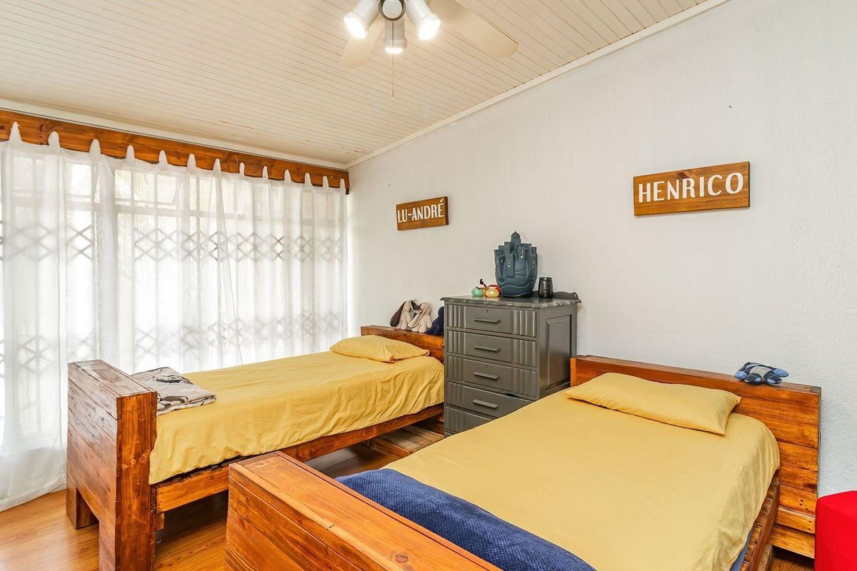 A bedroom featuring timber ceiling panels, laminate flooring, and a security gate over the window.