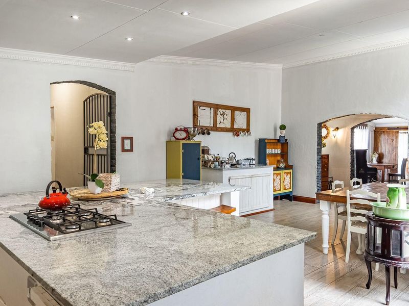 Spacious open-plan kitchen and dining area featuring a large granite island with integrated gas hob, recessed lighting, and elegant arched architectural details.