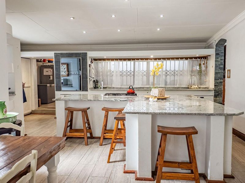 Spacious open-plan kitchen featuring granite countertops, a built-in gas hob, and recessed lighting, seamlessly flowing into the dining area.