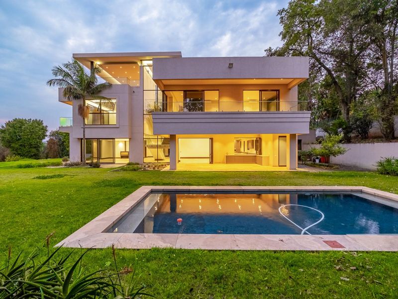 Modern multi-story residence featuring a spacious rear garden, swimming pool, covered patio, and expansive glass sliding doors for seamless indoor-outdoor living.