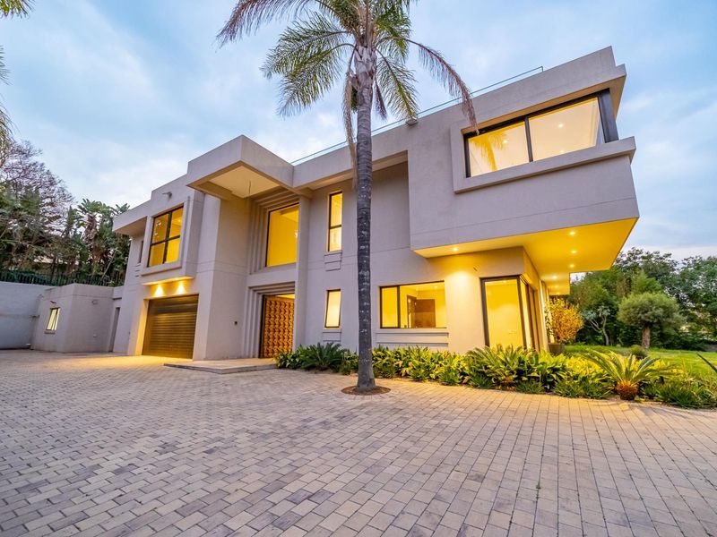 A modern double-storey residential property featuring a paved driveway, integrated garage, and contemporary architectural design with recessed exterior lighting.