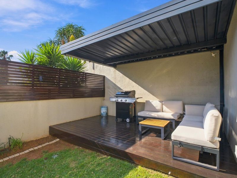 A well-maintained covered patio featuring timber decking and a privacy screen, providing an ideal outdoor space for relaxation and entertaining.