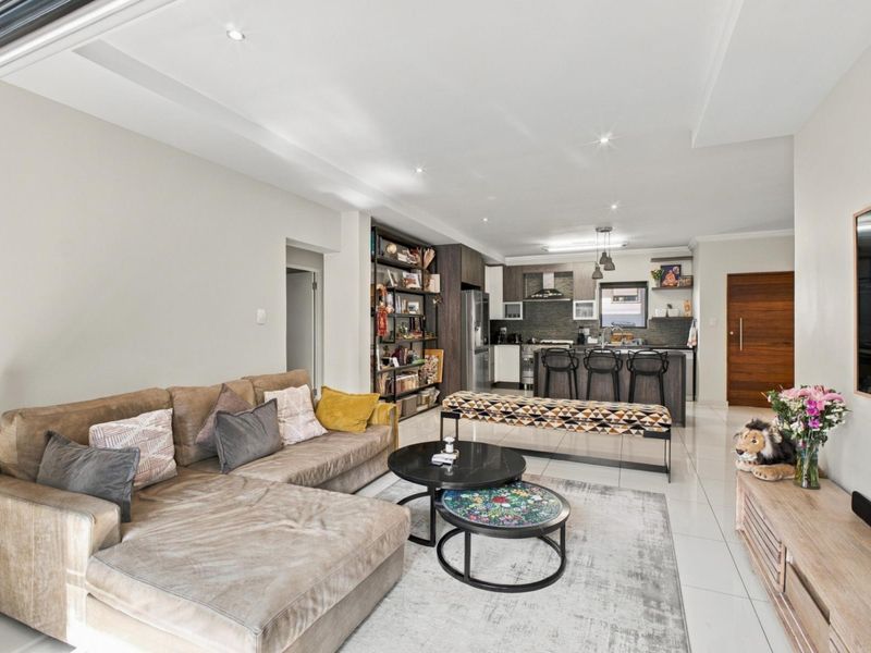 Spacious open-plan living area featuring a modern kitchen with island, stone countertops, and sleek cabinetry, seamlessly flowing into the comfortable lounge space.