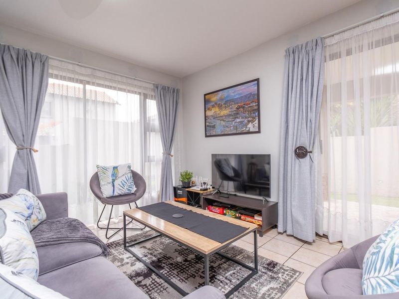 A bright and comfortable living room featuring tiled flooring and large sliding glass doors that provide ample natural light and access to the outdoors.