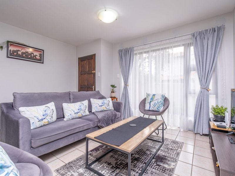 A comfortable living room featuring tiled flooring and a large sliding glass door that provides natural light.