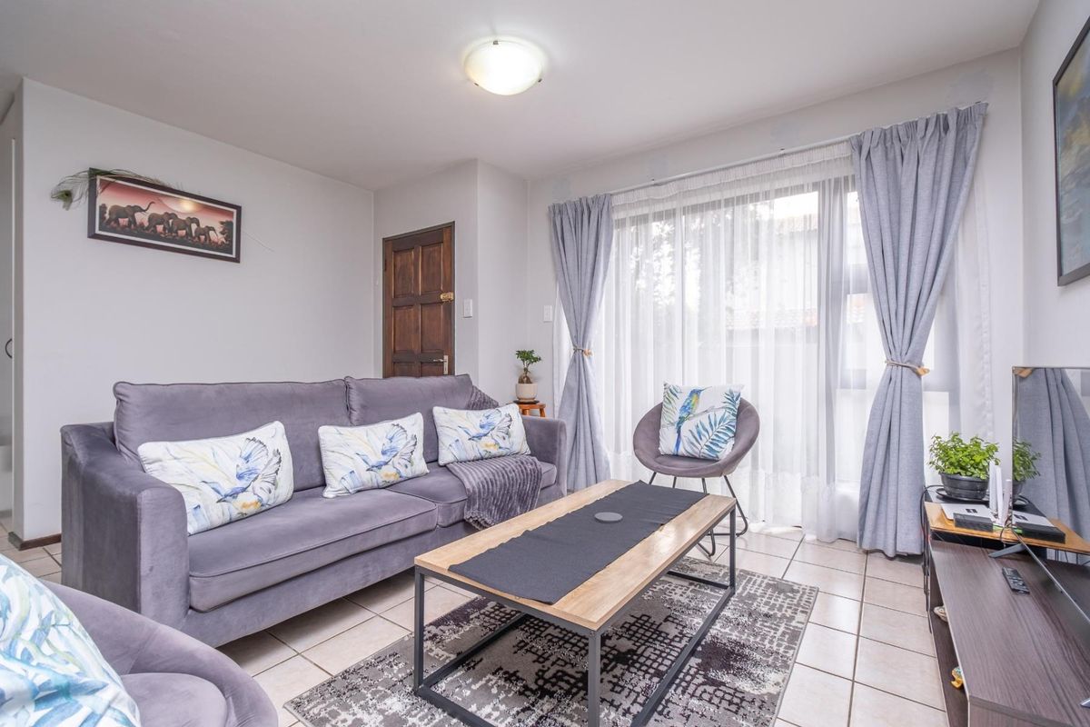 A comfortable living room featuring tiled flooring and a large sliding glass door that provides natural light.