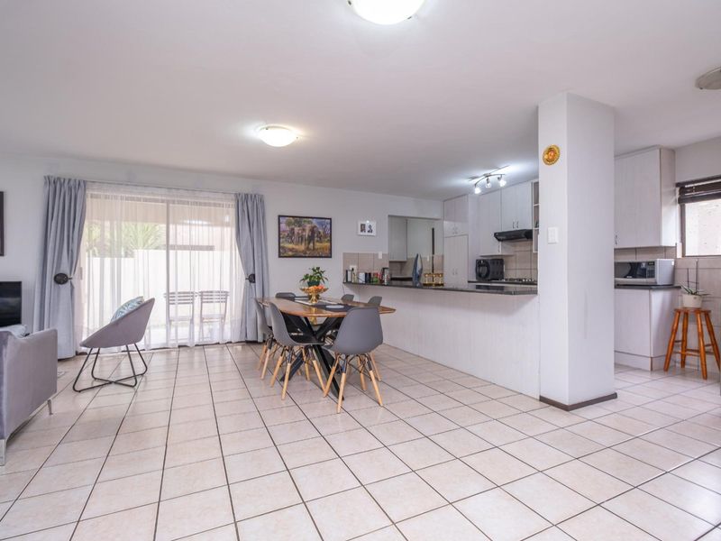 Open-plan living and dining area featuring tiled floors, a functional kitchen with granite countertops, and sliding glass doors leading to the patio.