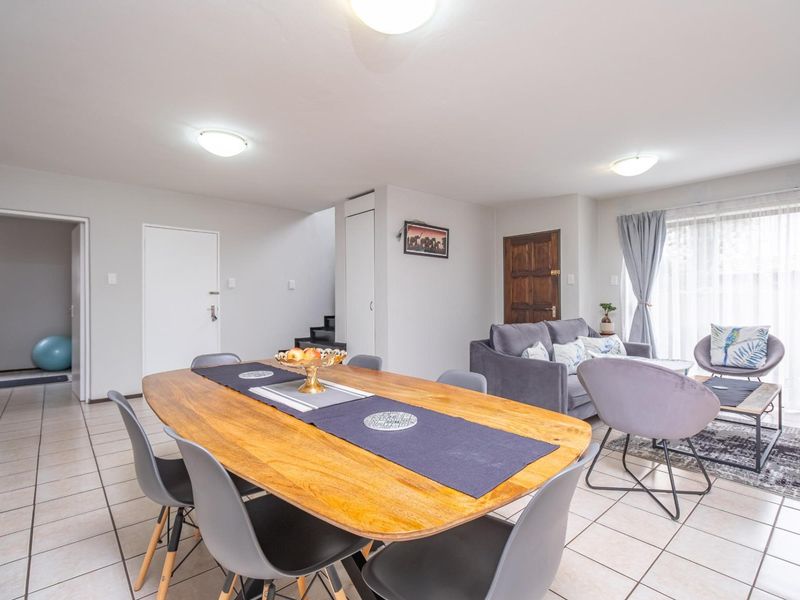 An open-plan living and dining area featuring neutral tiled flooring, ample natural light from sliding doors, and functional built-in storage.