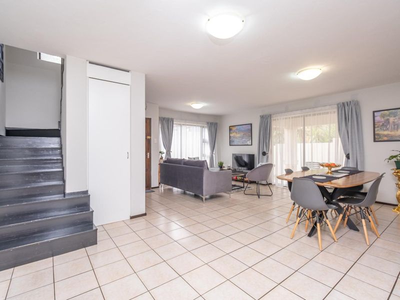 Spacious open-plan living and dining area featuring tiled flooring, a staircase, and sliding glass doors providing access to the exterior.