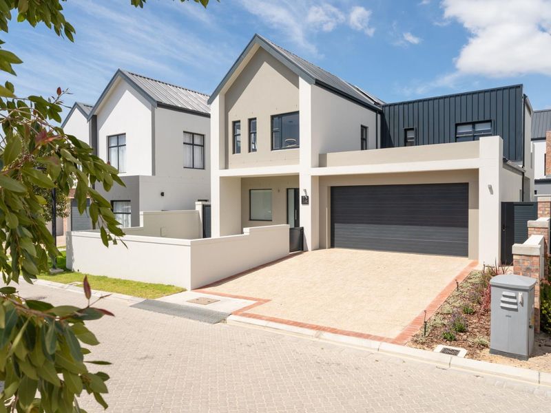 Modern double-story residential home featuring a contemporary facade, integrated double garage, and paved driveway in a secure estate setting.