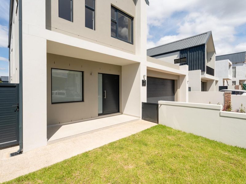 Modern double-storey home exterior featuring a clean facade, integrated garage, paved entrance walkway, and a well-maintained front lawn.