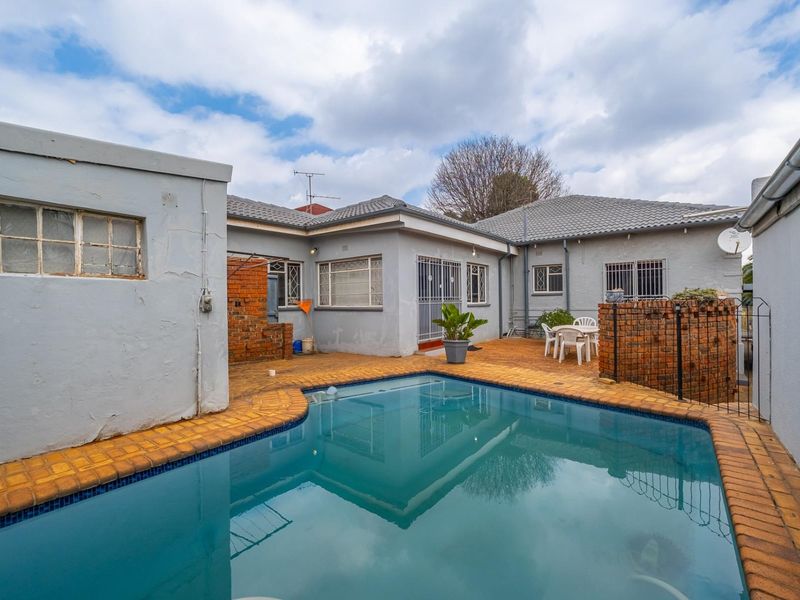 Rear courtyard area featuring a swimming pool with brick paving and surrounding brick boundary walls.