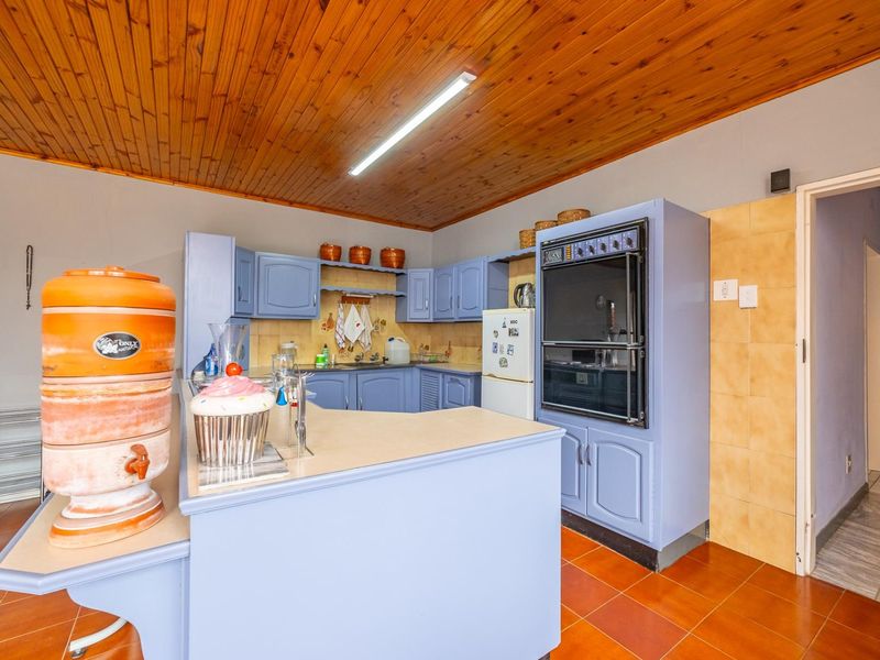 A dated kitchen featuring blue built-in cabinetry, a double wall oven, laminate countertops, and a timber-clad ceiling.