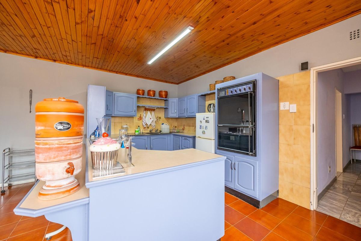 A dated kitchen featuring blue built-in cabinetry, a double wall oven, laminate countertops, and a timber-clad ceiling.
