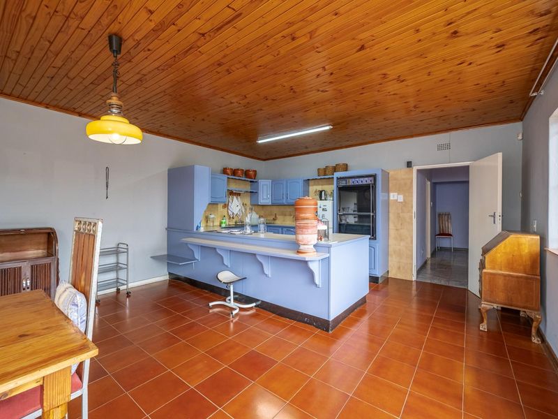Open plan kitchen and dining area featuring tiled floors, timber ceiling, and blue built-in cabinetry with a breakfast bar.