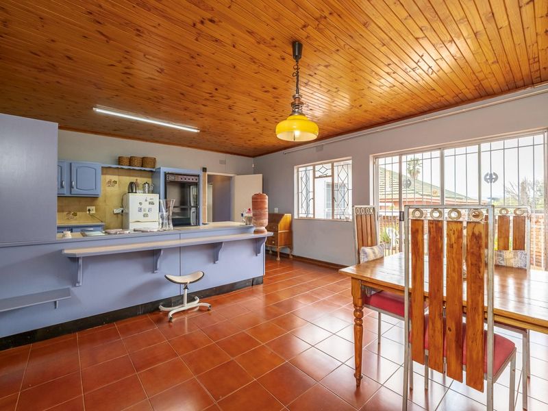 Open plan kitchen and dining area featuring a timber ceiling, tiled flooring, and a breakfast bar with direct access to the patio.