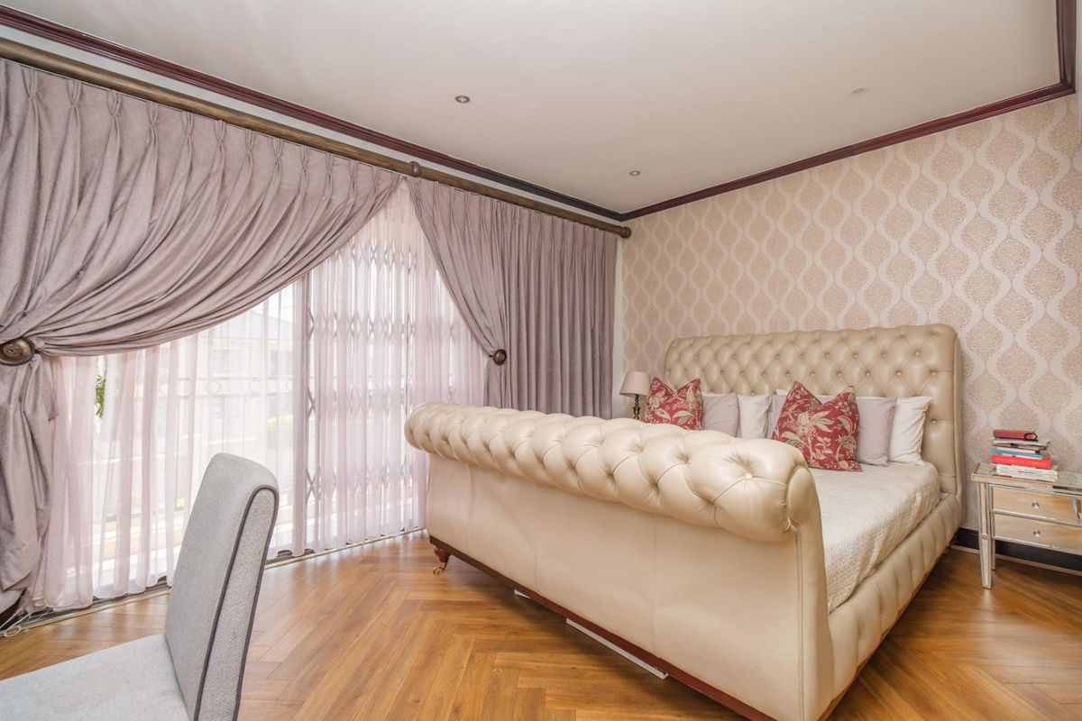 A well-maintained bedroom featuring herringbone wood flooring, decorative wallpaper, recessed lighting, and a sliding glass door with an integrated security gate.