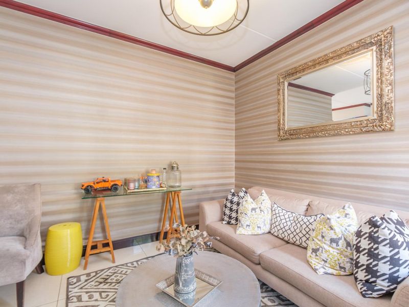 A cozy living room featuring striped wallpaper, tiled flooring, and decorative crown molding, providing a comfortable and well-defined space.